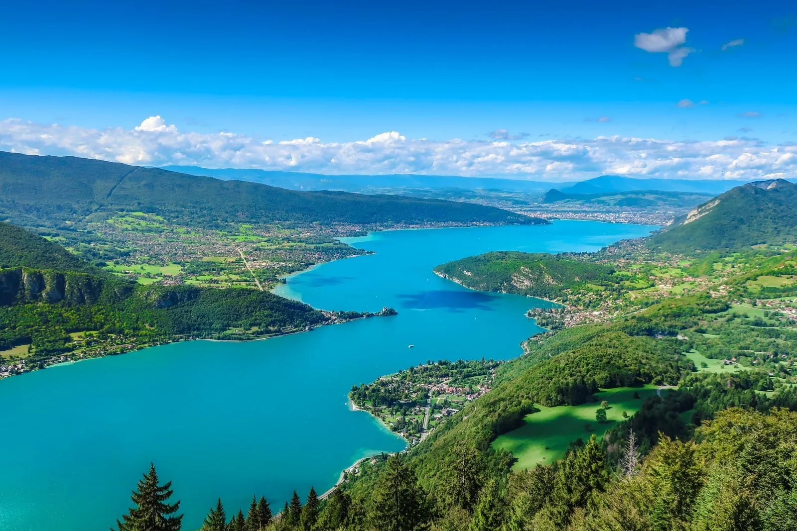 Le lac d’Annecy turquoise vu des hauteurs de la rive est, sous le soleil d’été.